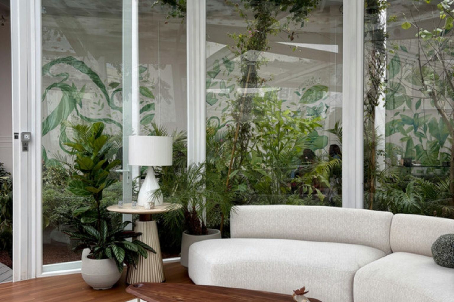 Lys udestue med hvid sofa, planter og store glaspartier